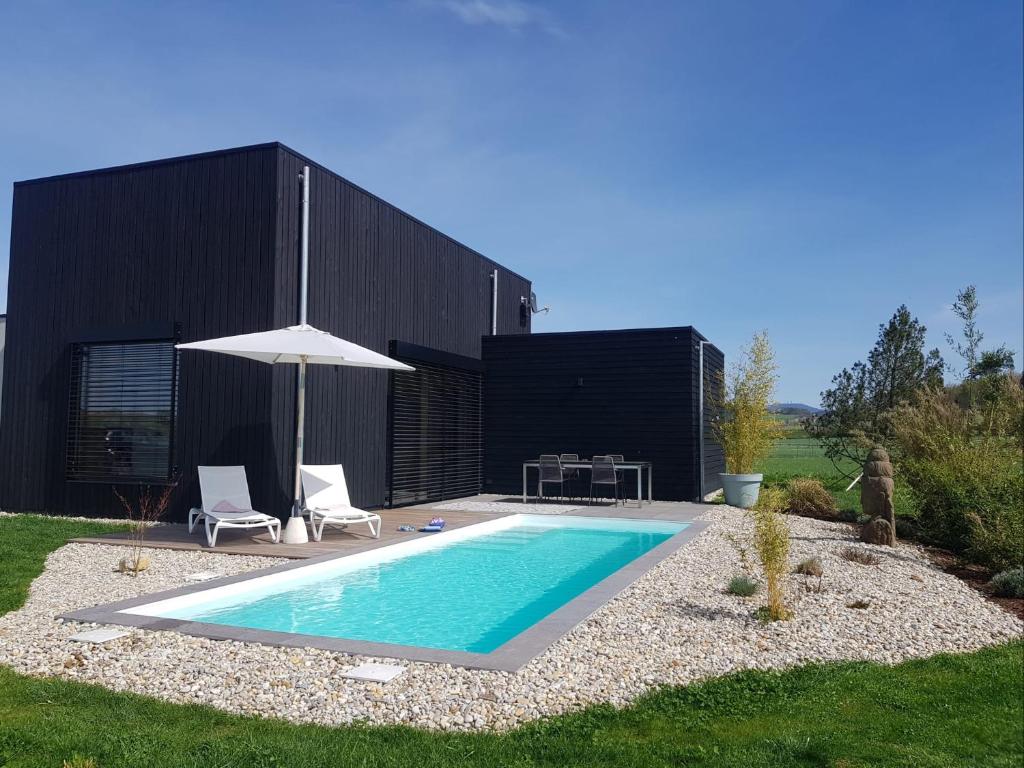 una piscina en un patio con sombrilla en Der Schwarzbau - Luxus Ferienhaus mit Pool und Sauna, en Runding
