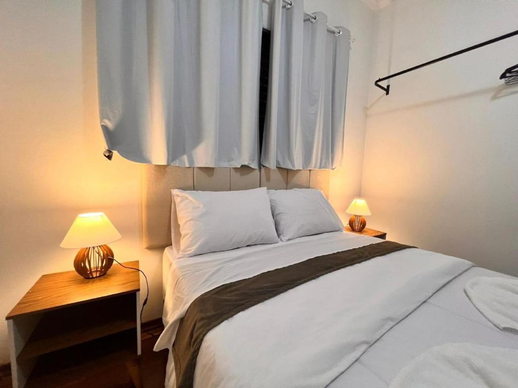 ein Schlafzimmer mit einem großen weißen Bett mit zwei Lampen in der Unterkunft Residencia Dago Suítes in Campos do Jordão