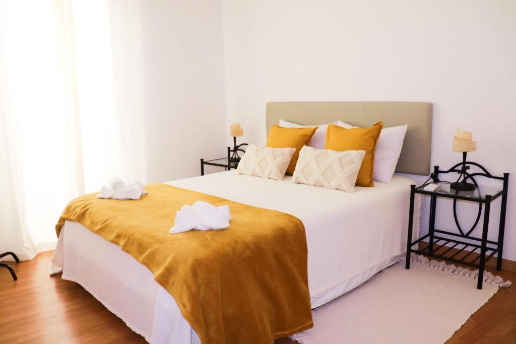 a bedroom with a large white bed with yellow pillows at Casa Amar- Vista panorâmica in Luz