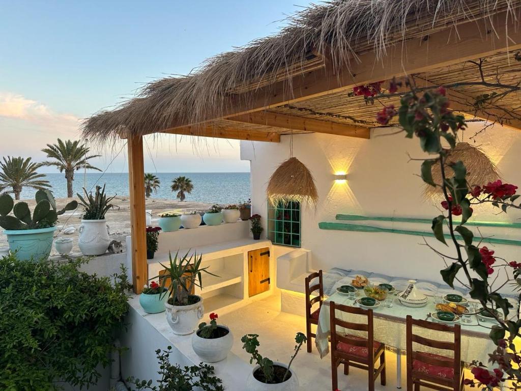 een patio met een tafel en stoelen en de oceaan bij Dar El Mahdia in Mahdia