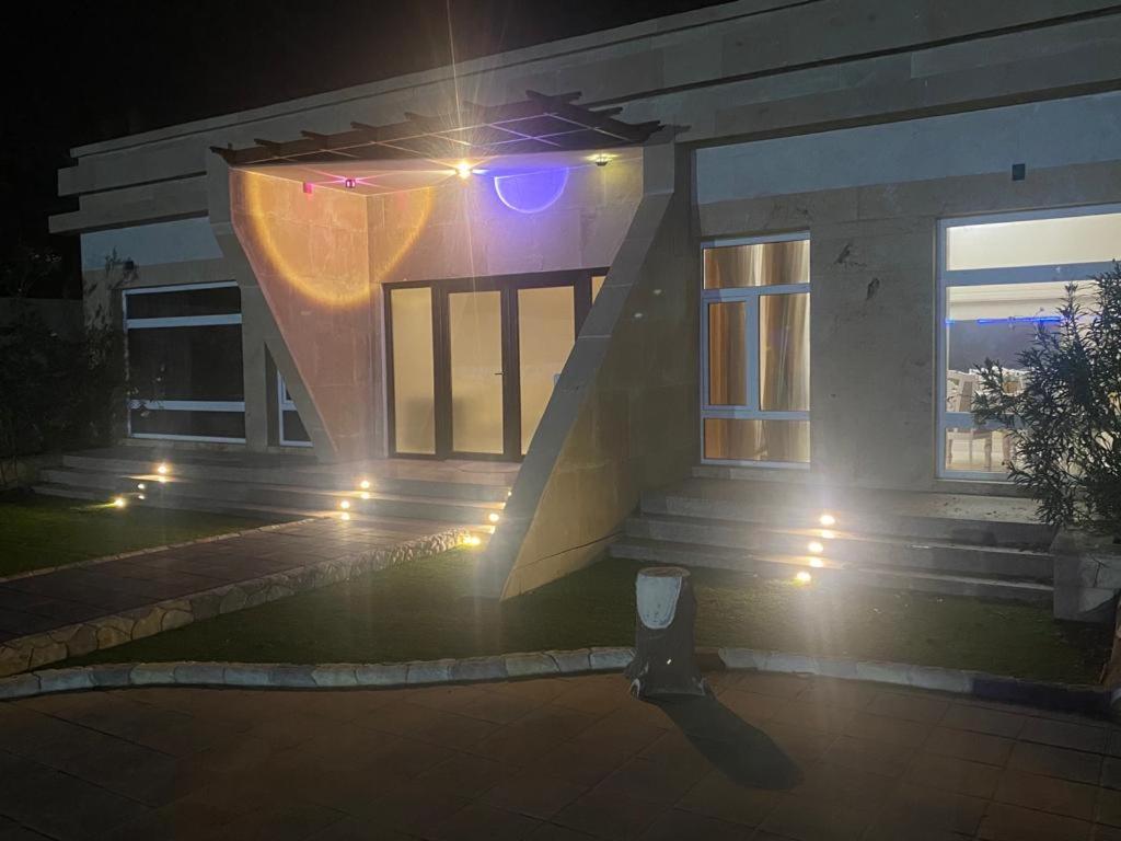 Aram luxurious five bedroom villa with pools & fountains في صحار: منزل فيه اضاءه في الليل