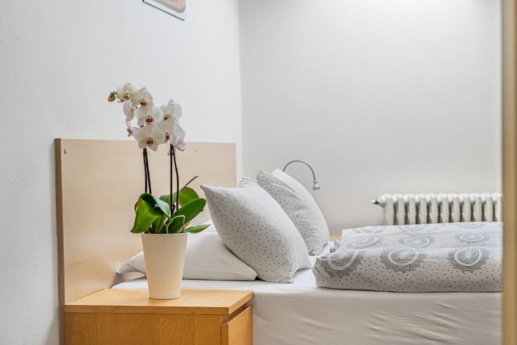 un vaso bianco con fiori bianchi su un letto di Apartmány Rozárka Turnov a Turnov