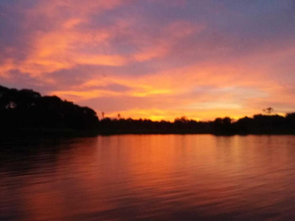 Siquirres的住宿－ESMERALDA LODGE，日落在水面上