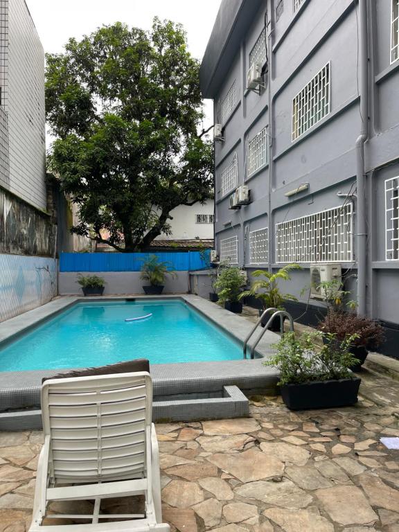 een zwembad met een stoel naast een gebouw bij Appartement ethnique cosy in Douala
