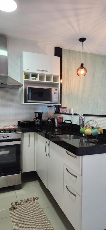 uma cozinha com armários brancos e um balcão preto em Golden Lake RJ - Lindo como um Resort! em Arraial do Cabo