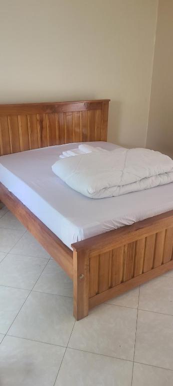 armazón de madera con colchón blanco en Solace Guest House, en Entebbe