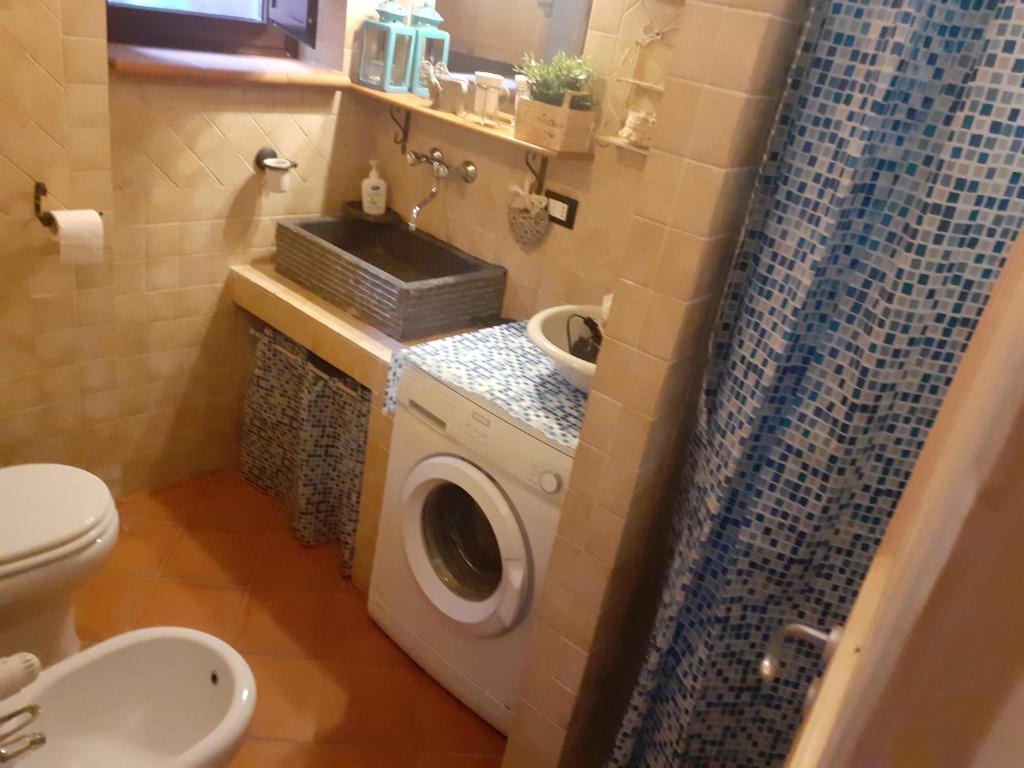ein Badezimmer mit einer Waschmaschine und einem Waschbecken in der Unterkunft CASA DOLCE CASA di Rosy e Roby in Bardine di San Terenzo Monti