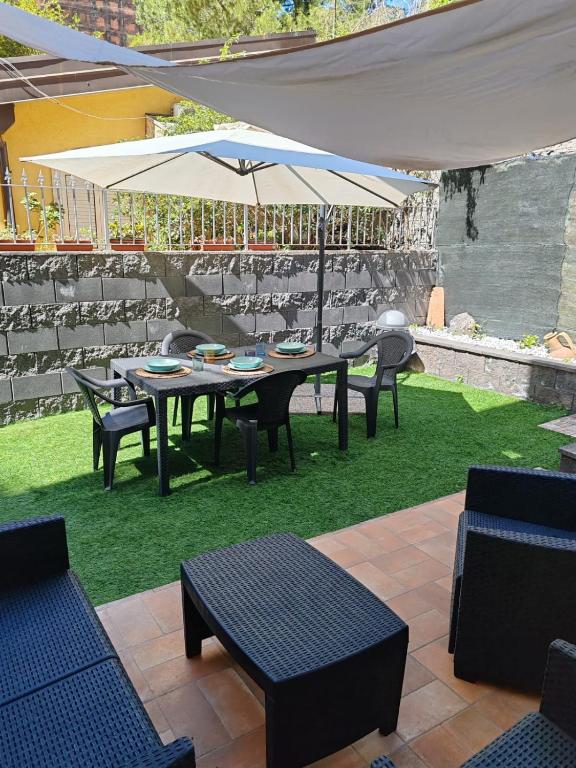 Etna Garden House: Oasis in the heart of Catania في كاتانيا: طاولة وكراسي مع مظلة على العشب