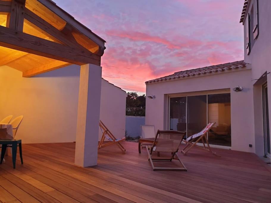 une terrasse avec des chaises et un coucher de soleil en arrière-plan dans l'établissement Maison familiale en version 10 pers. plage à 300 m, à LʼÉpine