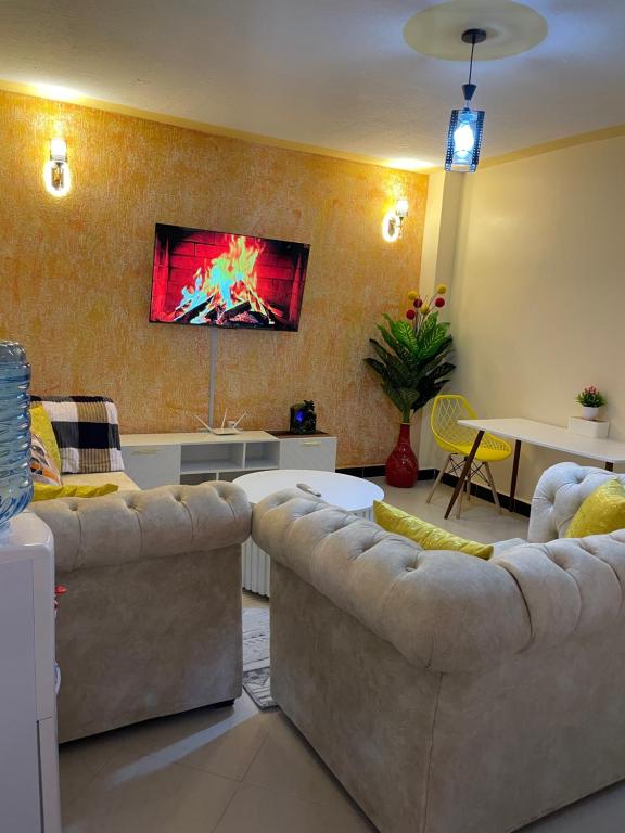 sala de estar con 2 sofás y TV en la pared en Executive Cozy Furnished Apartment-In Utawala, NBO, Near JKIA, en Nairobi