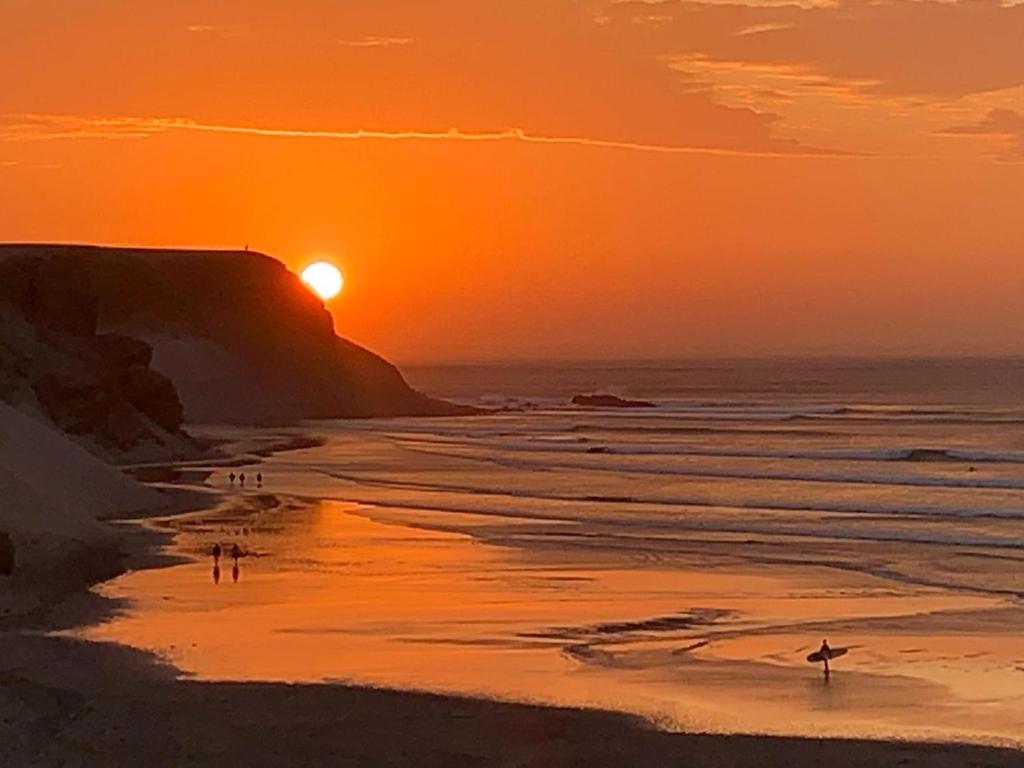 a group of people walking on the beach at sunset at Family Surf Chicama in Puerto Chicama