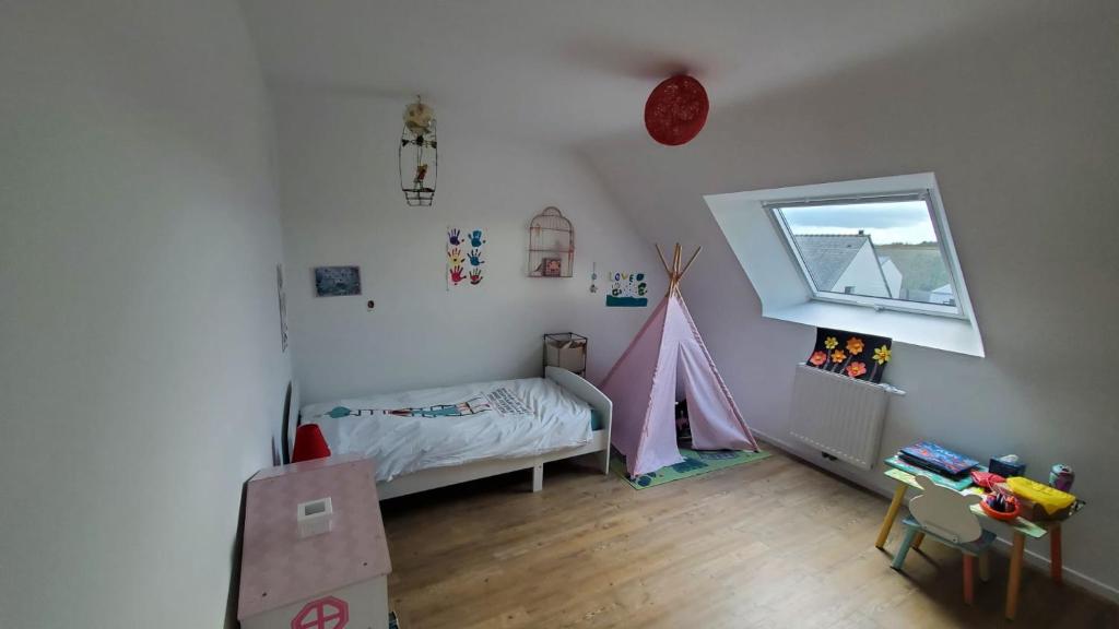 - une chambre pour enfants avec un lit et une fenêtre dans l'établissement Maison proche du centre, à Auray