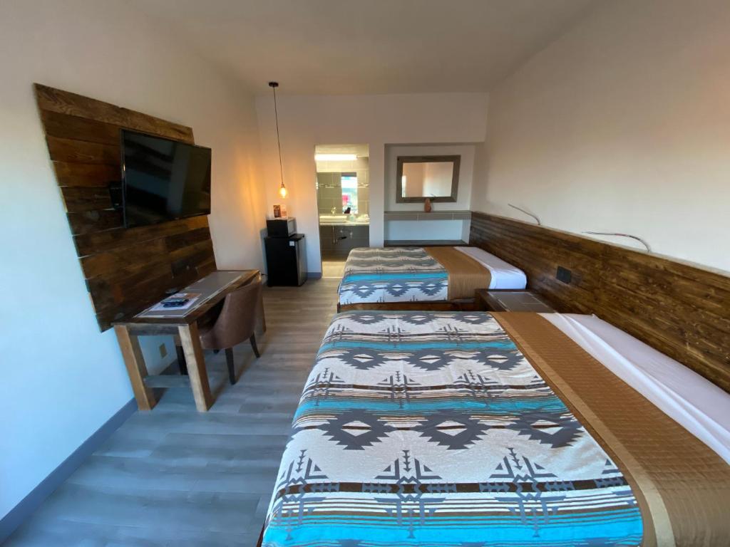 a hotel room with two beds and a flat screen tv at Neon Cowboy Roadhouse at Hunters Hot Springs in Lakeview