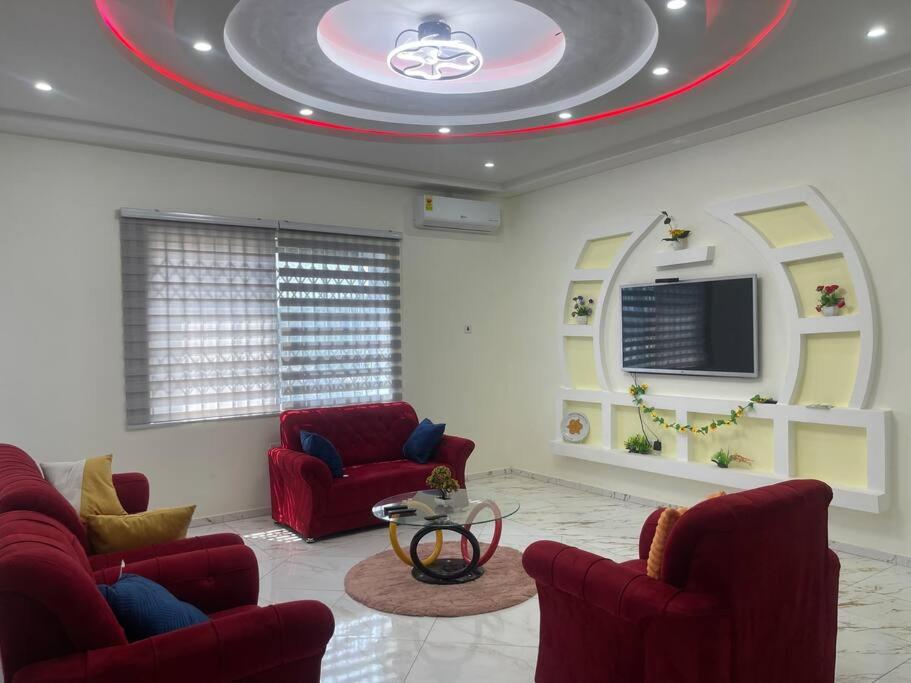 a living room with two red chairs and a tv at Amazing Grace Apartment in Cape Coast