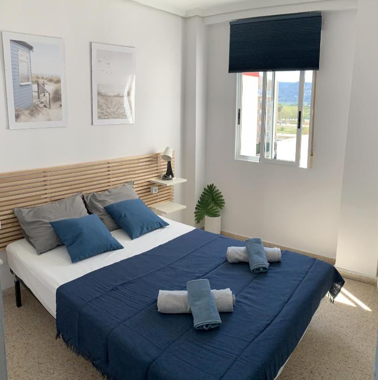 a bedroom with a large bed with blue sheets and pillows at Apartamento El Sol in Piles