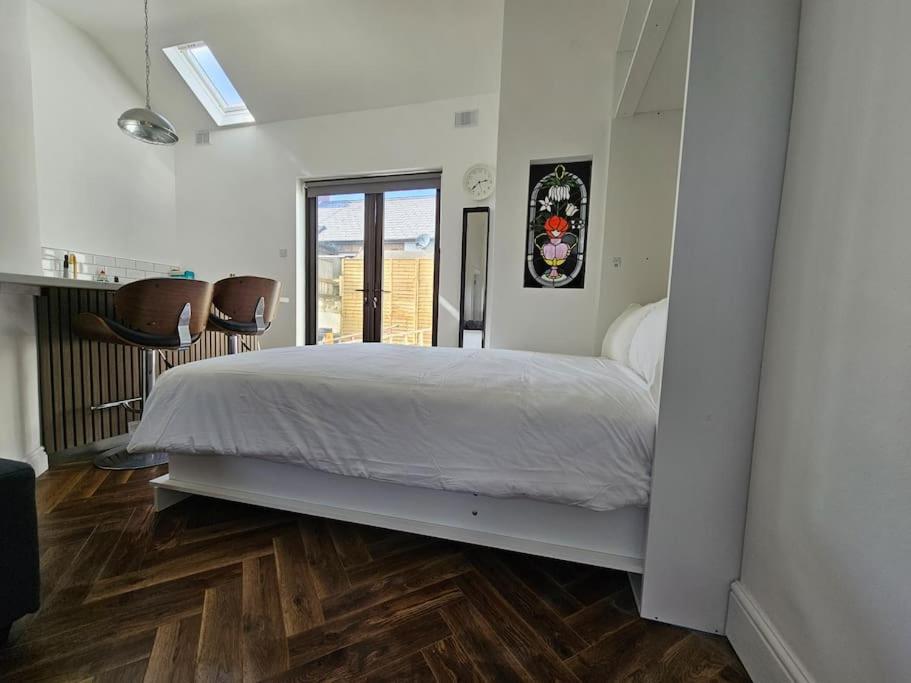 a bedroom with a white bed and a wooden floor at Charming House in City Centre in Dublin