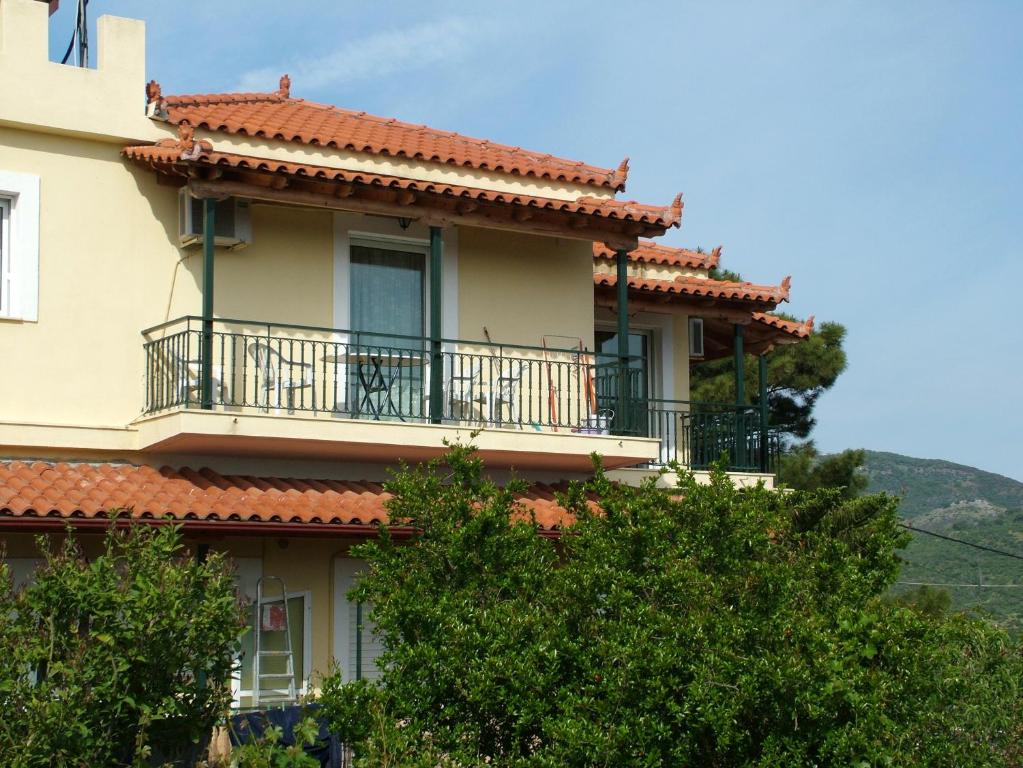 una casa con balcón y árboles en la parte delantera en Thalis Rooms, en Skoutari