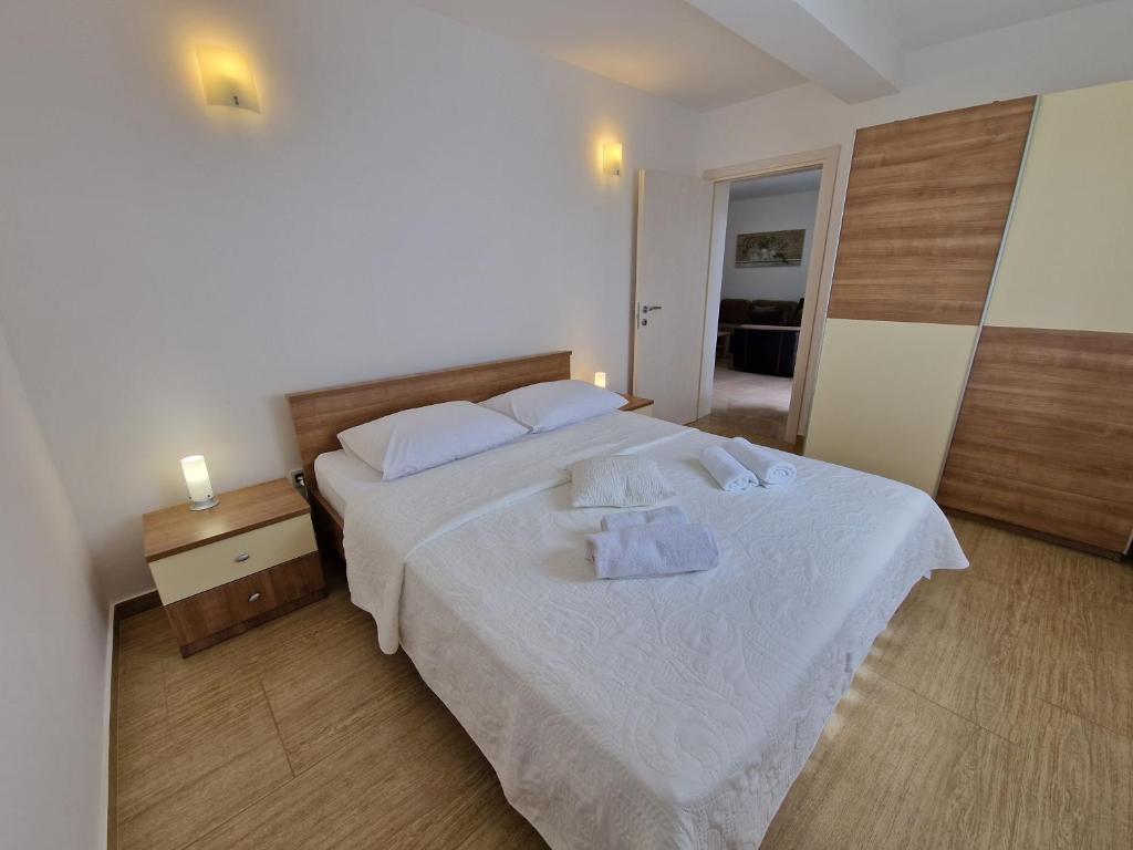 Un dormitorio con una cama blanca con toallas. en Apartments Maslina, en Baška