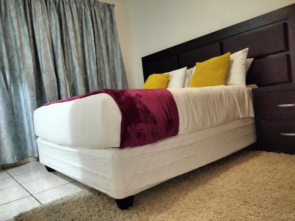 una camera da letto con un letto con cuscini bianchi e gialli di Apartment on MR103 a Mbabane