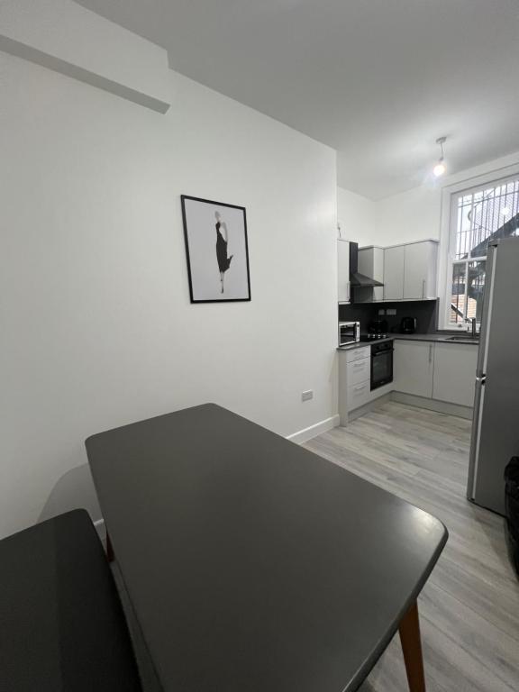 倫敦的住宿－London rooms，白色的厨房配有桌子和冰箱