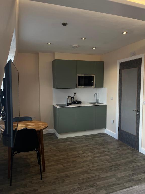 a kitchen with green cabinets and a table at The Lily Aparts in London