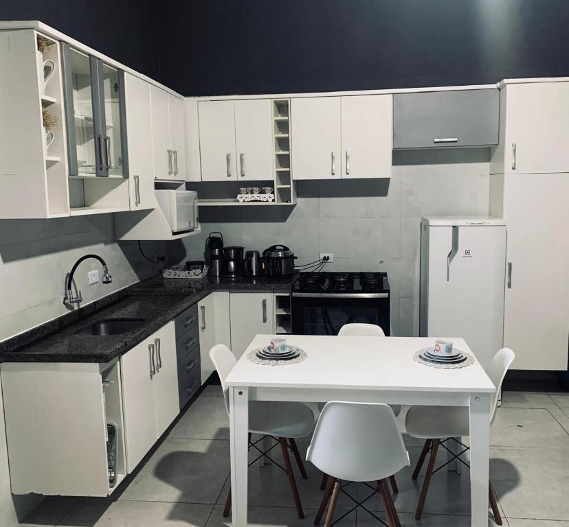 uma cozinha com armários brancos e uma mesa e cadeiras brancas em Loft Eco City 02-Espaçoso e Confortável c/ Garagem em Curitiba
