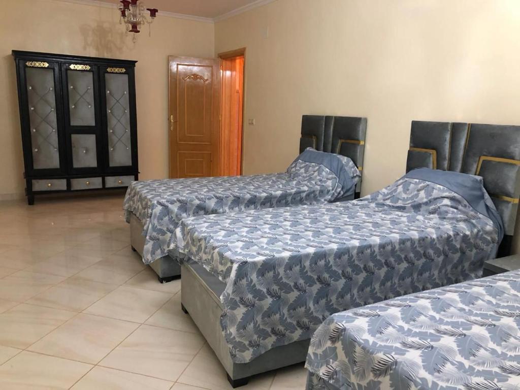 een kamer met drie bedden en een deur bij Residence al Rahma 02 in Monte ʼArrouit