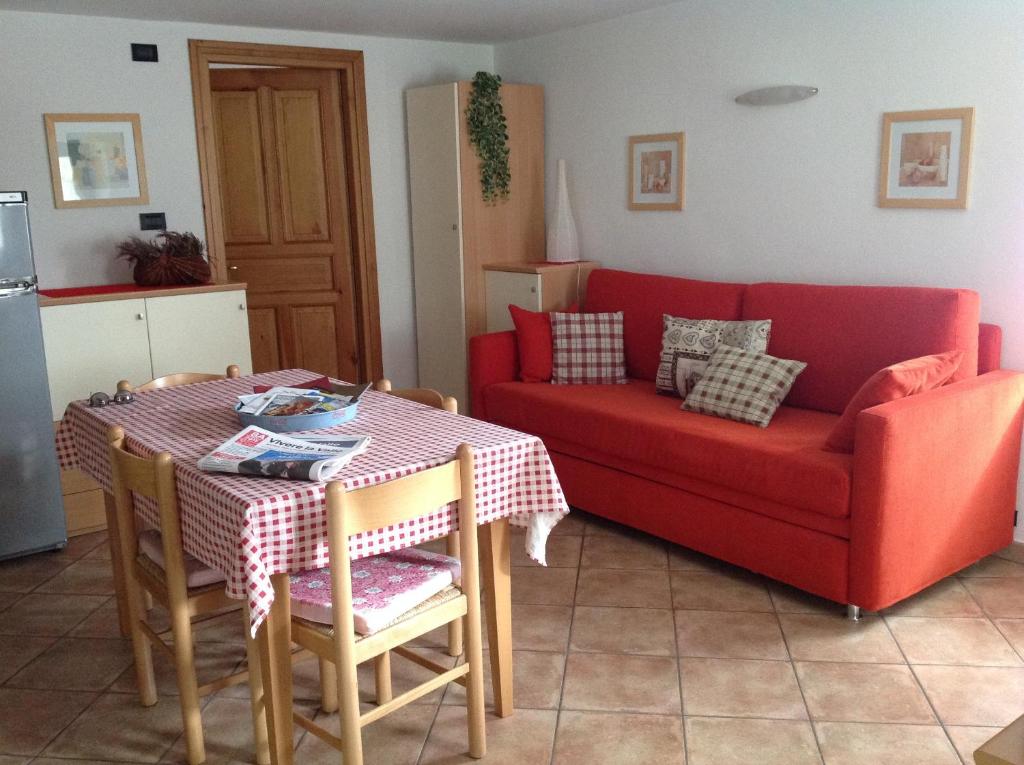 a living room with a red couch and a table at La Maison de Mémé in Fontainamore