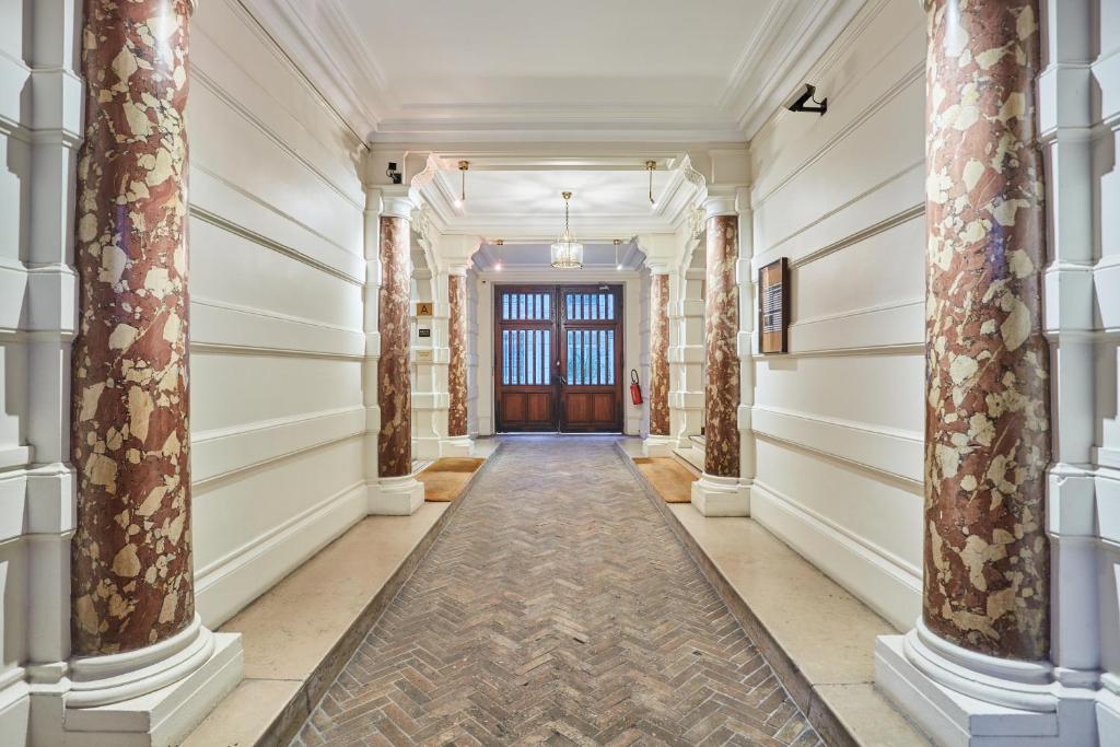 a hallway of a building with columns and a door at Petites chambres rénovées 2024 Paris 17e in Paris