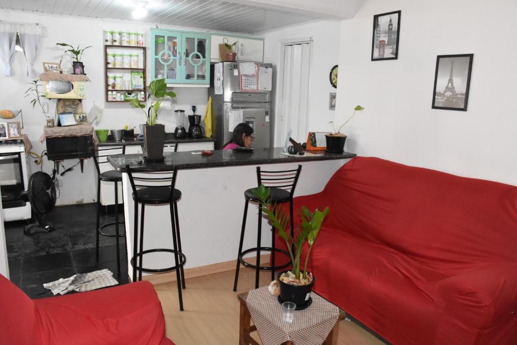 a living room with a red couch and a kitchen at Hostel Cascavel in Cascavel