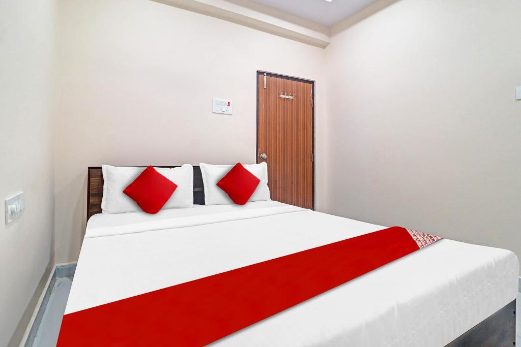 um quarto com uma cama branca e almofadas vermelhas em Hotel SV Grand em Hyderabad