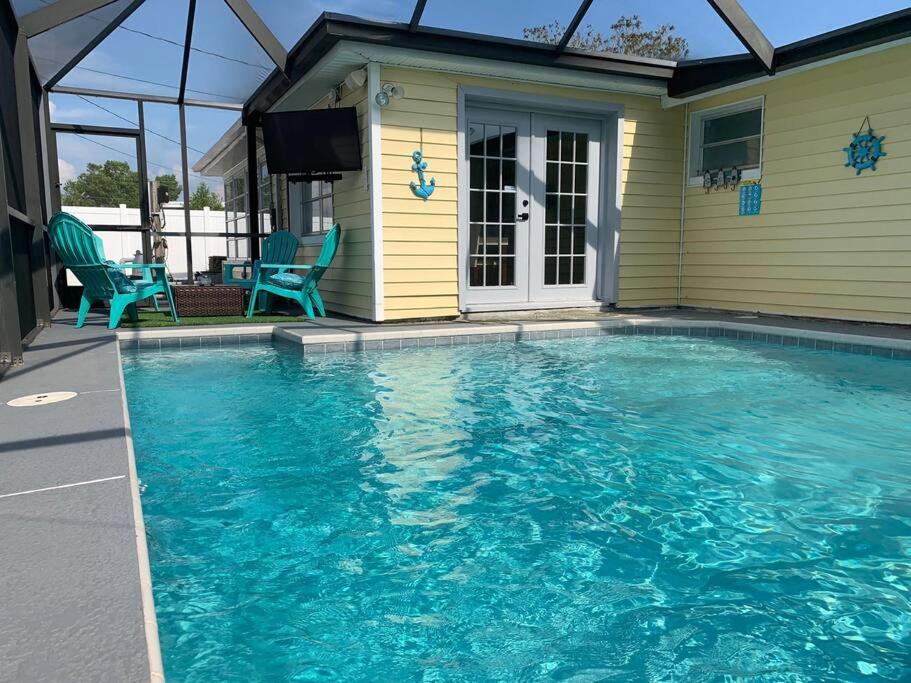 een zwembad met blauwe stoelen en een huis bij Coastal Comfort: Unwind in Style at Our Two-Bedroom Haven with Private Pool in Holiday