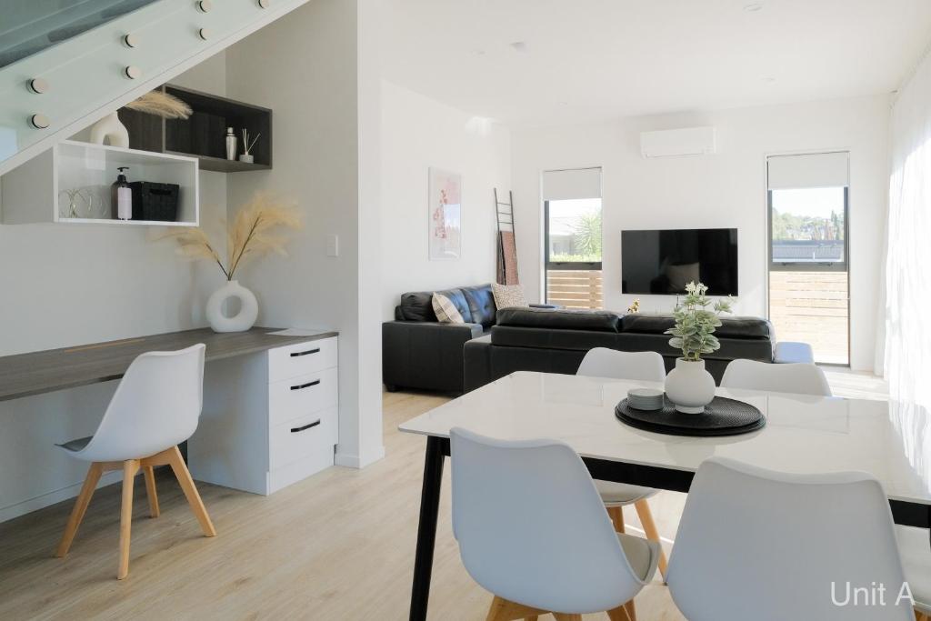 uma sala de estar branca com uma mesa e cadeiras brancas em Modern Howick Town House Fibre WiFi Netflix em Auckland