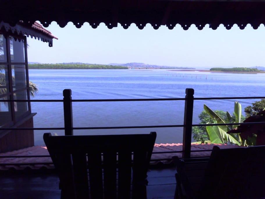 d'un balcon offrant une vue sur une grande étendue d'eau. dans l'établissement WOODEN CHALET ON THE RIVER BANKS, à Vieux-Goa