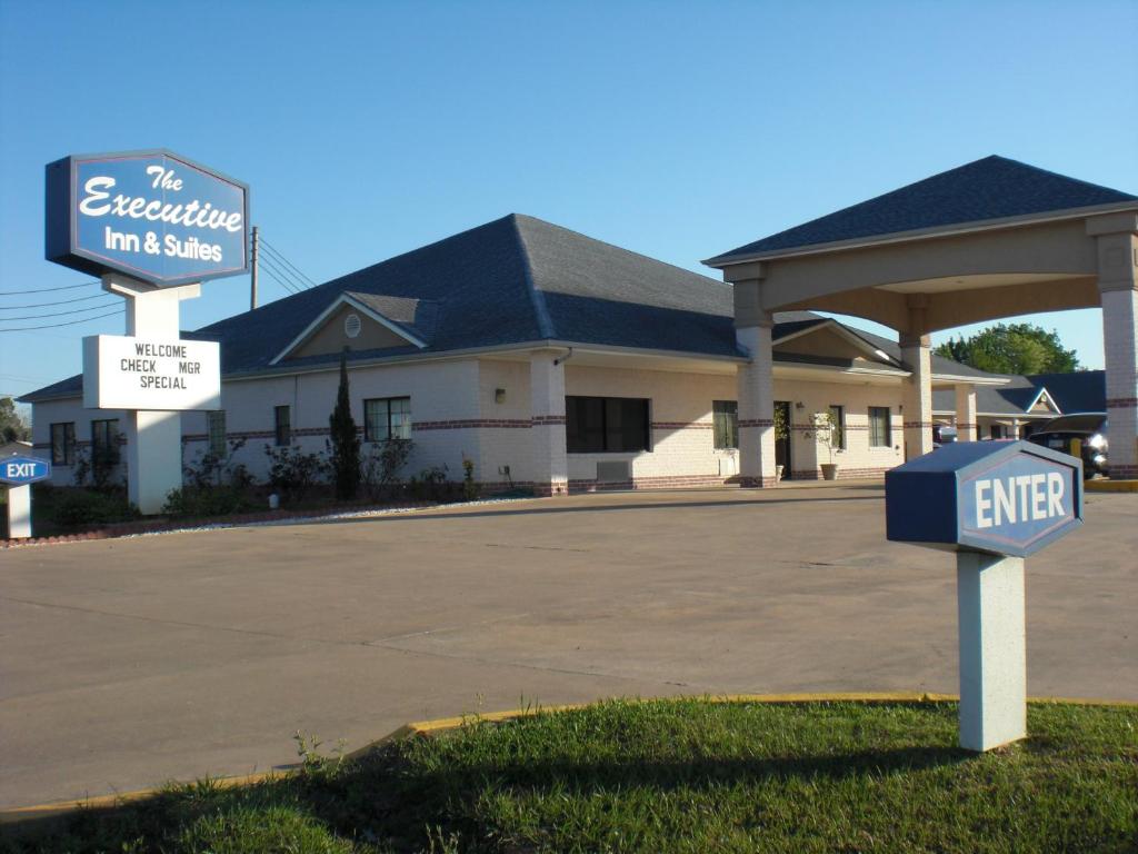 un edificio con un cartel delante de un aparcamiento en Executive Inn & Suites West Columbia, en West Columbia