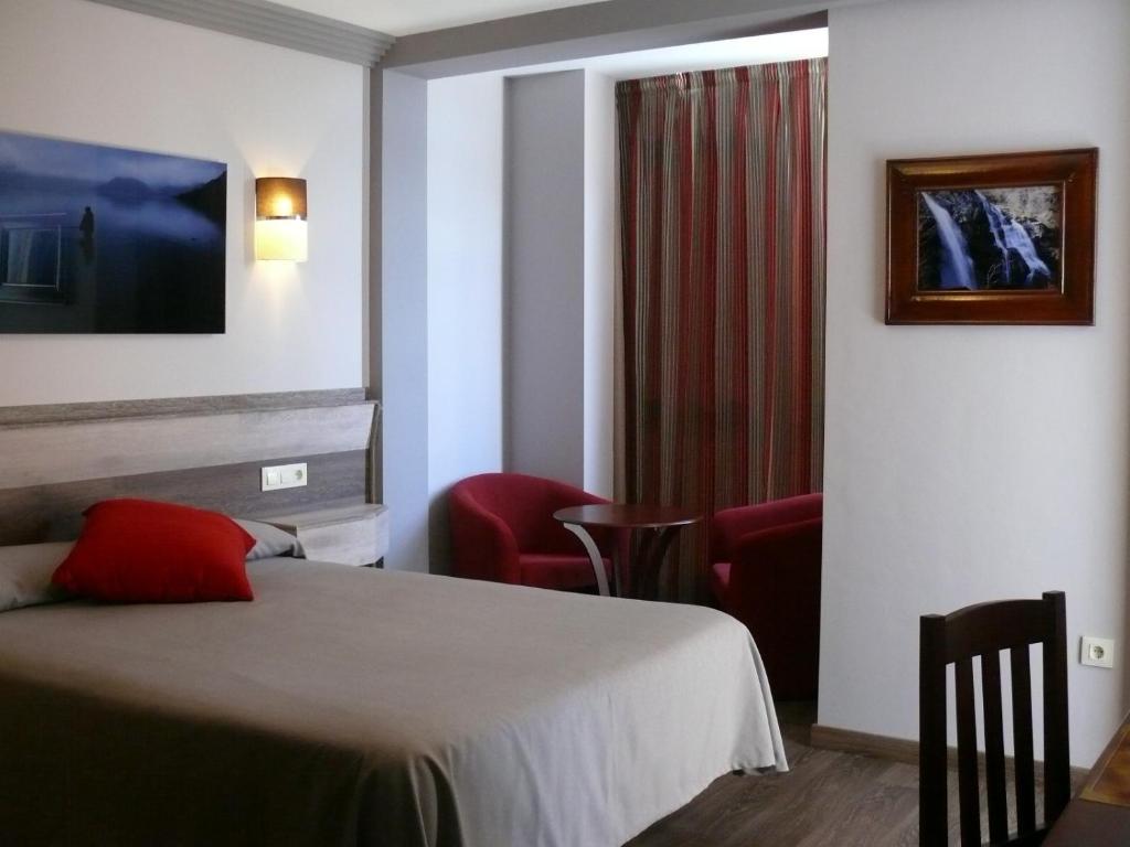 um quarto de hotel com uma cama e duas cadeiras em Hotel Gran Casona de Sanabria em Puebla de Sanabria