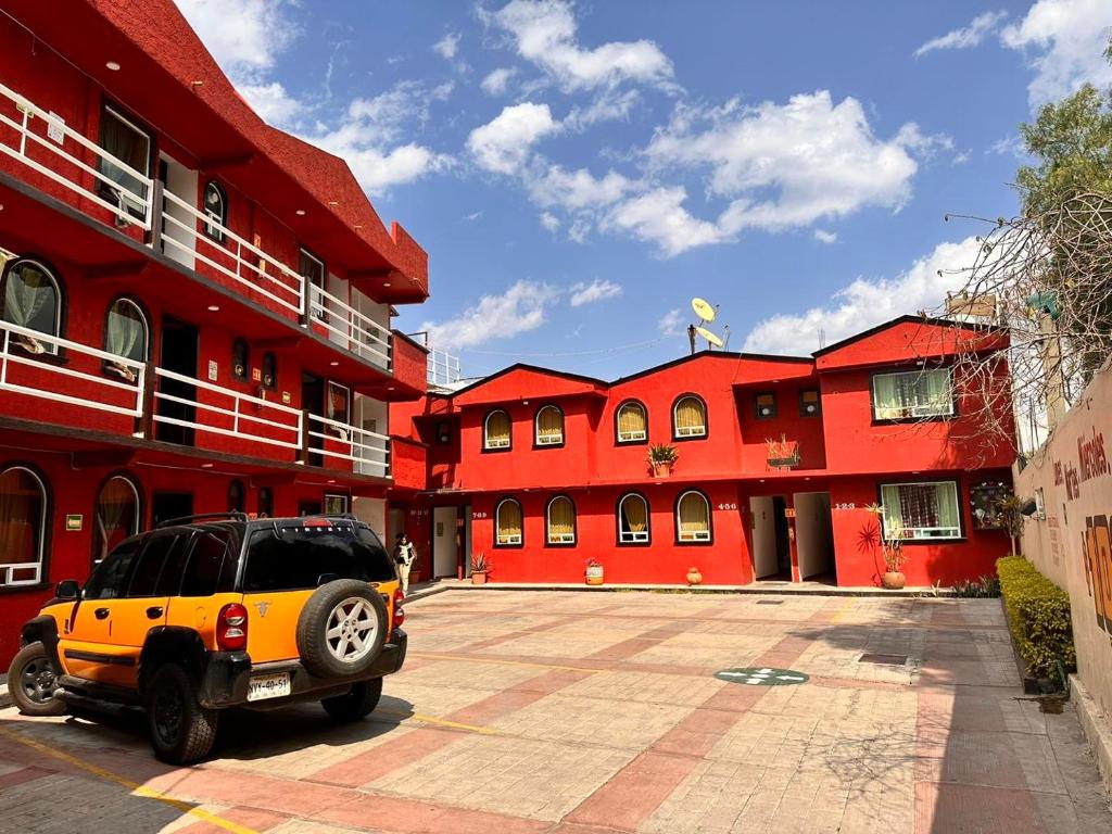 une voiture garée devant un bâtiment rouge dans l'établissement Paléis, à Santa Cruz Tecamac