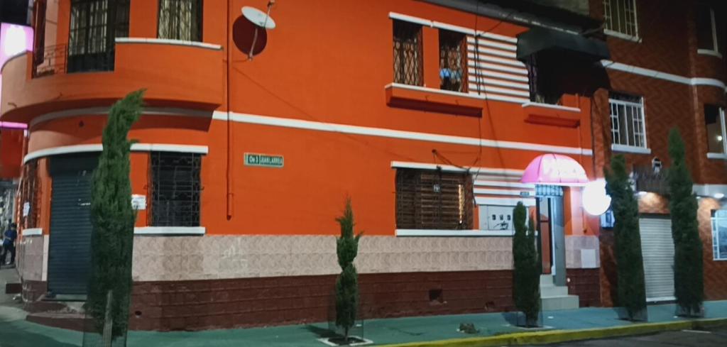 an orange building with trees in front of it at HOSTAL CALIFORNIA in Quito