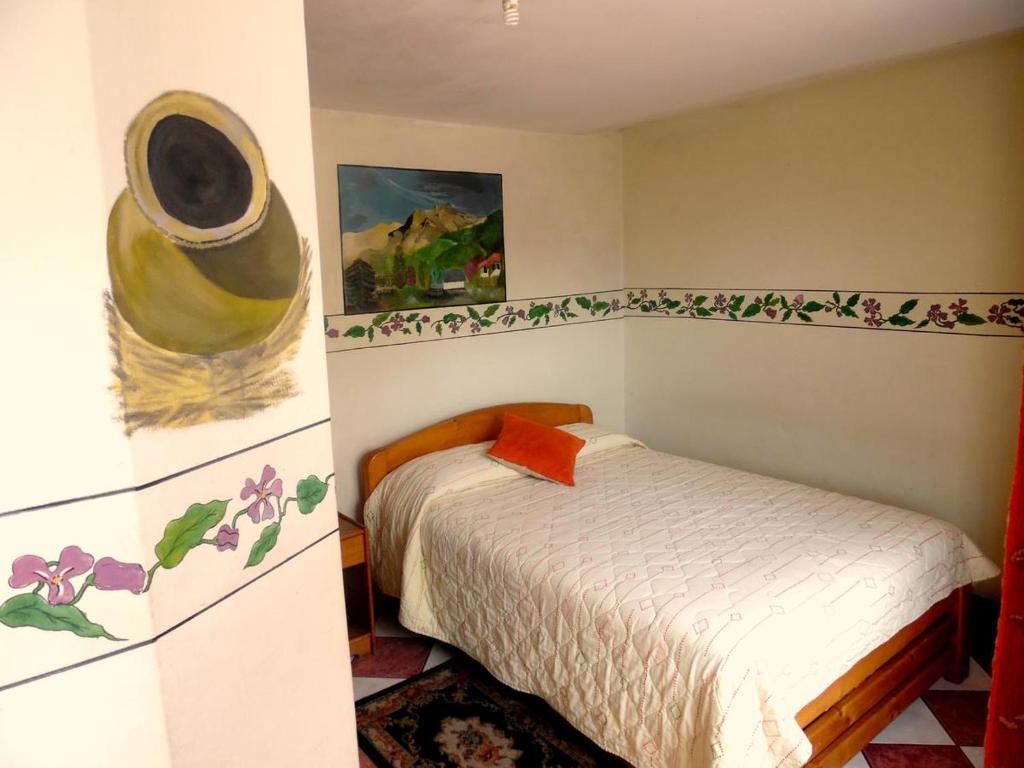 1 dormitorio con 1 cama y una pintura en la pared en Hostal Rincón Del Turista, en Otavalo