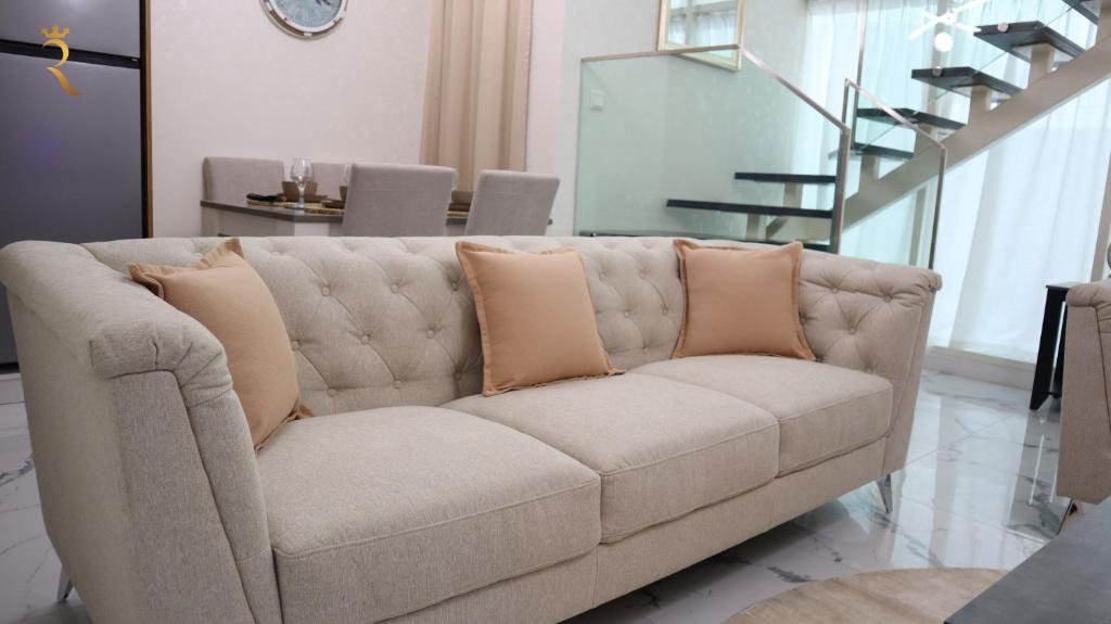 a couch with pillows on it in a living room at Chalet 2BR Duplex Apartment in Abu Dhabi
