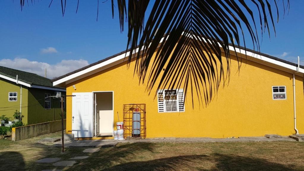 una casa amarilla con una palmera delante de ella en LaMaison en Ocho Rios