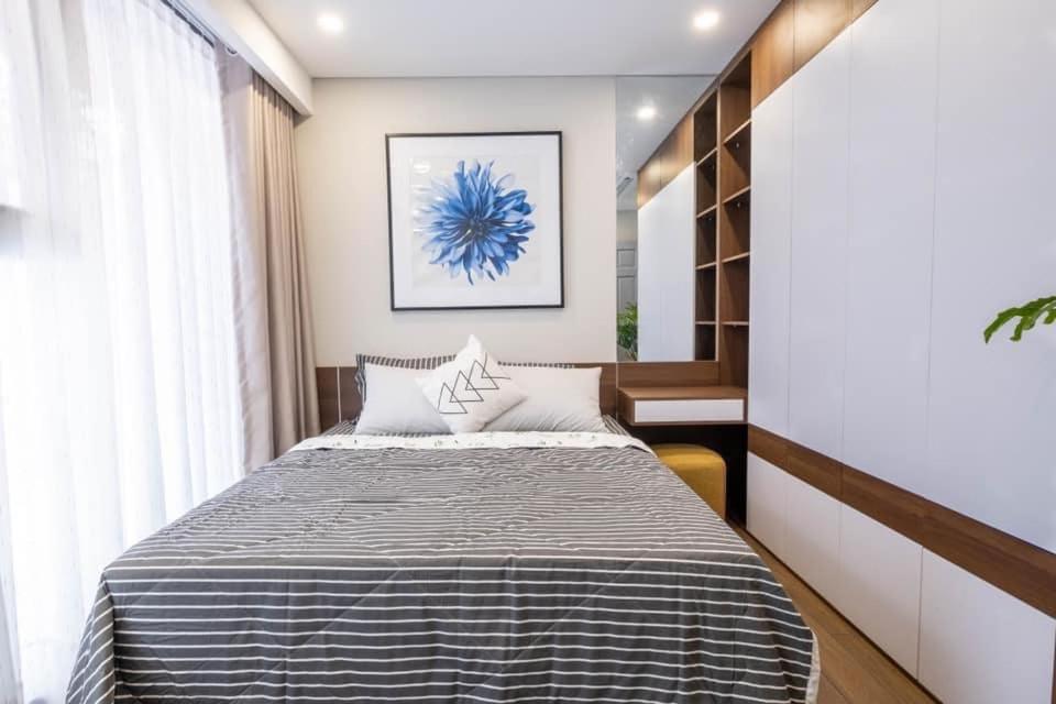 een slaapkamer met een bed met een blauw schilderij aan de muur bij Louisa Vinh Hoi Apartment in Ho Chi Minh-stad
