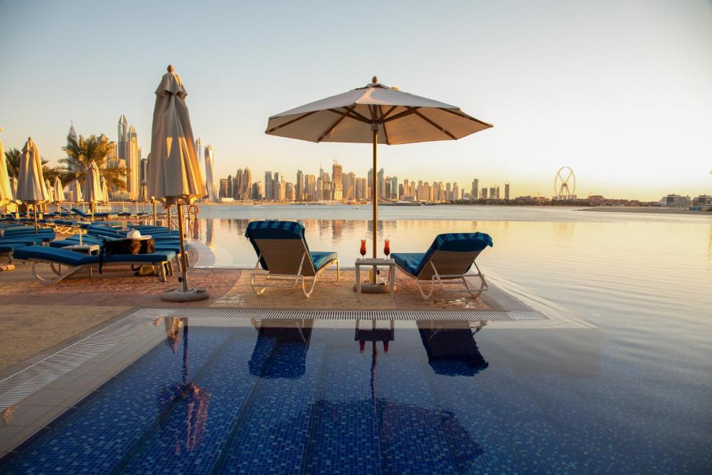 a pool with chairs and an umbrella next to the water at Oceana Atlantic Seaside Apt in Dubai