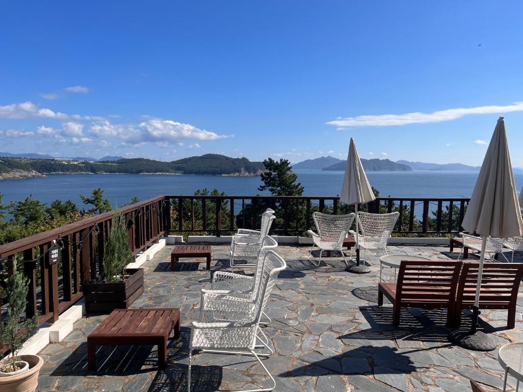 een patio met stoelen en tafels met uitzicht op het water bij Country House Exclamation Mark & Comma in Namhae