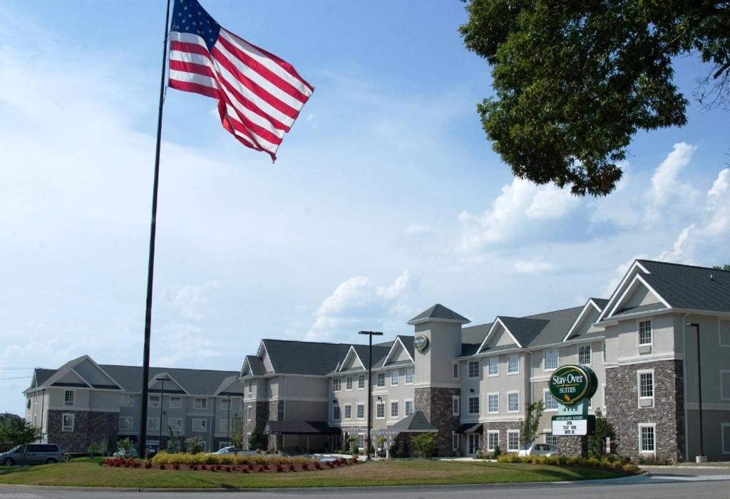 una bandera americana ondeando frente a un hotel en Stay-Over Suites - Fort Gregg-Adams Area en Hopewell