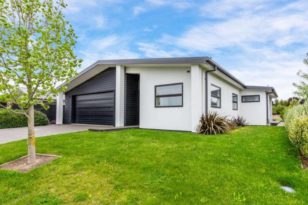 una casa blanca con césped verde en Rolleston Lodge, en Christchurch