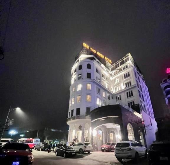 un grand bâtiment blanc avec des voitures garées devant lui dans l'établissement Tam Đảo Gold Hotel, à Tam Ðảo