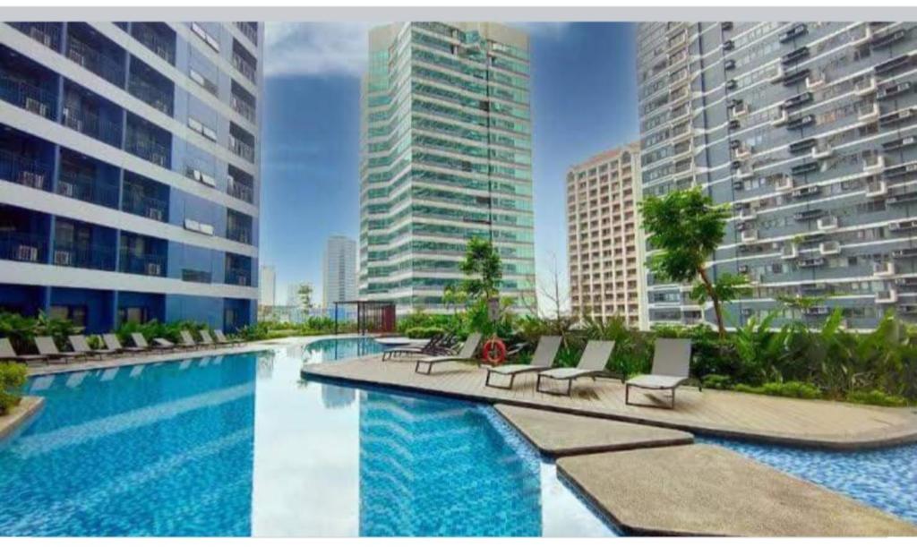 una piscina con sedie a sdraio e alcuni edifici di UNIT 4765 AIR a Manila