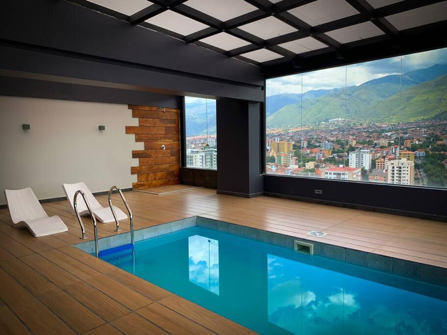 una piscina con 2 sillas y vistas a la ciudad en Piso 17: la mejor vista en Cala Cala cerca de todo, en Cochabamba