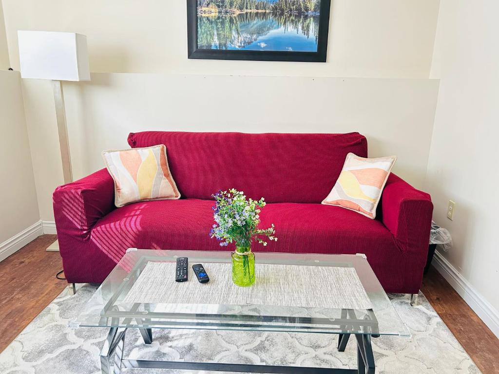 a red couch in a living room with a table at Basement unit with 2 bedrooms, bath and living area in Lower Sackville